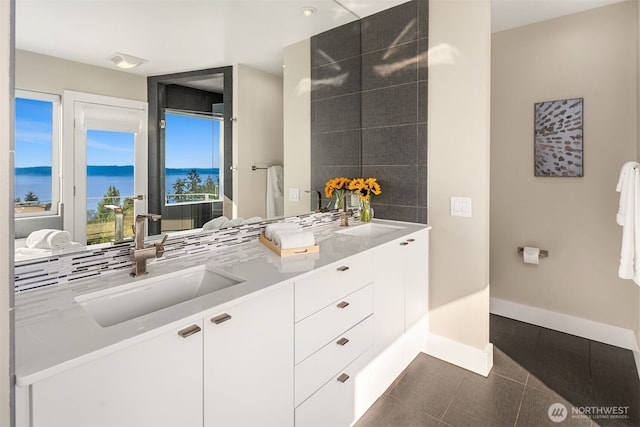 bathroom with double vanity, baseboards, and a sink