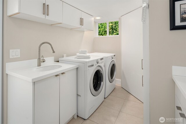 clothes washing area featuring a sink, cabinet space, washing machine and dryer, and light tile patterned floors