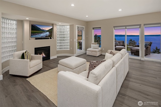 living area featuring recessed lighting, baseboards, dark wood-type flooring, and a glass covered fireplace