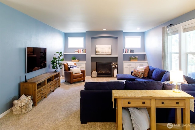 living room featuring recessed lighting, baseboards, light carpet, and a glass covered fireplace