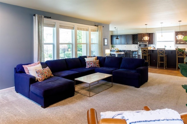 living area with baseboards and light carpet