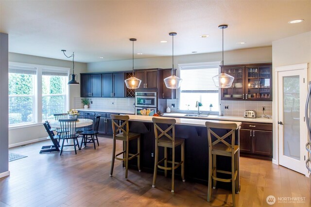 kitchen featuring glass insert cabinets, light wood-type flooring, a breakfast bar, and light countertops