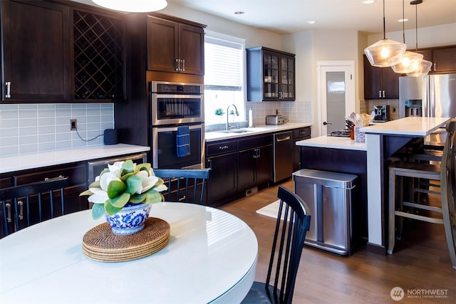 kitchen with appliances with stainless steel finishes, light countertops, dark wood-type flooring, and a sink