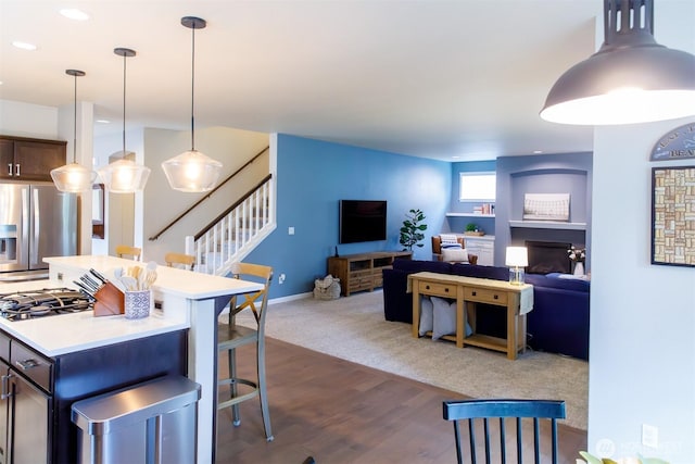 kitchen featuring a center island, stainless steel fridge with ice dispenser, open floor plan, light countertops, and a fireplace