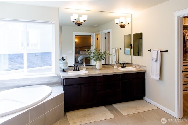 bathroom featuring double vanity, connected bathroom, a bath, and a sink