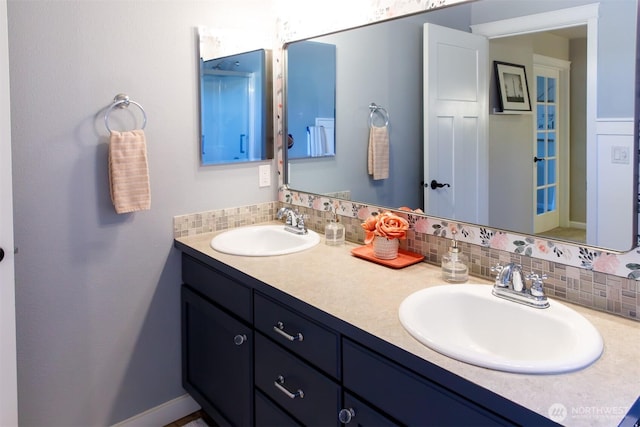 full bathroom featuring double vanity, tasteful backsplash, and a sink