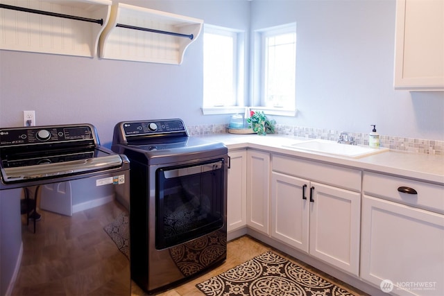 clothes washing area with independent washer and dryer and a sink