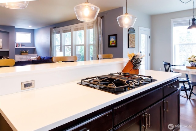 kitchen featuring dark wood finished floors, light countertops, pendant lighting, black gas stovetop, and open floor plan