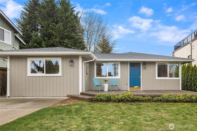 single story home featuring a wooden deck, a shingled roof, and a front lawn