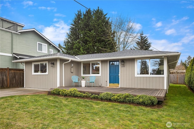 view of front of property featuring roof with shingles, a front lawn, and fence