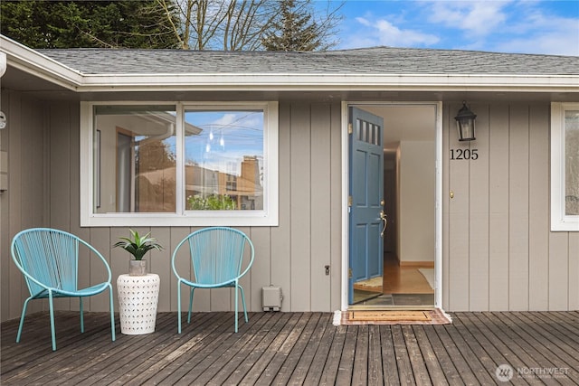 doorway to property featuring a deck and a shingled roof