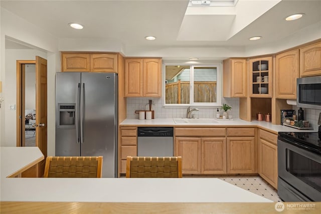 kitchen featuring a sink, glass insert cabinets, appliances with stainless steel finishes, and decorative backsplash