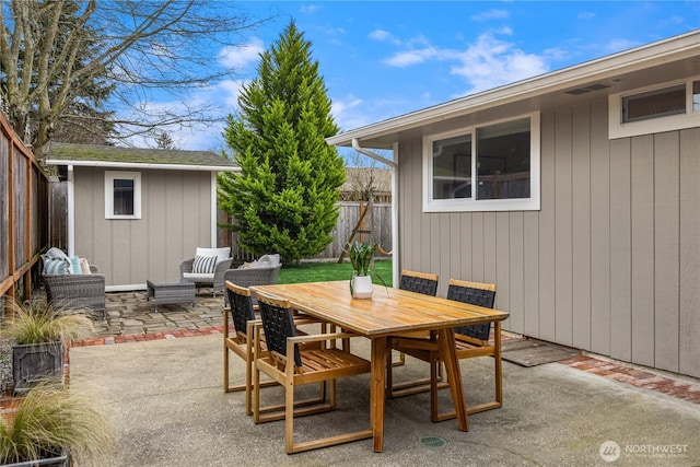 view of patio with a storage unit, a fenced backyard, an outbuilding, and outdoor dining space