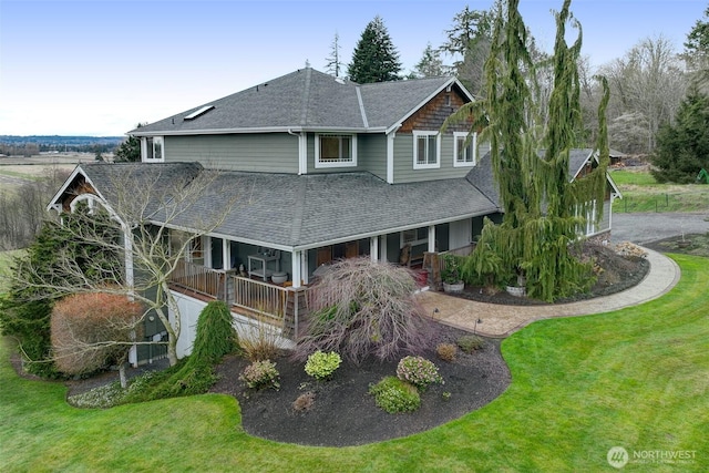 view of front of property with roof with shingles and a front lawn