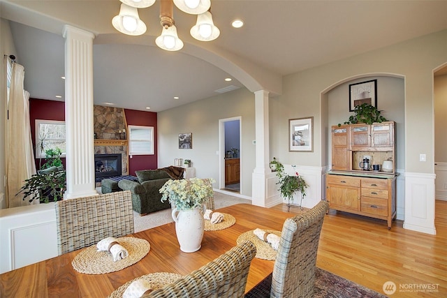 dining area with visible vents, light wood-style floors, a wainscoted wall, and ornate columns