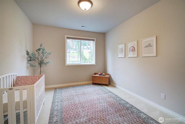 unfurnished bedroom featuring visible vents, a nursery area, baseboards, and carpet floors