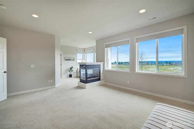 unfurnished living room featuring recessed lighting, carpet, visible vents, and a multi sided fireplace