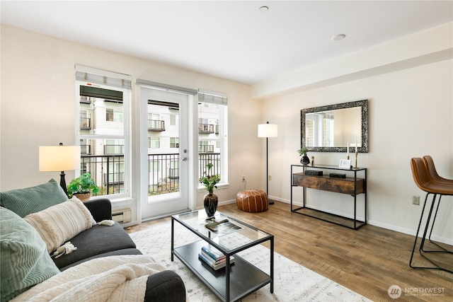 living room with a baseboard heating unit, wood finished floors, and baseboards