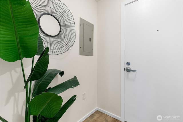 interior space featuring electric panel, baseboards, and wood finished floors