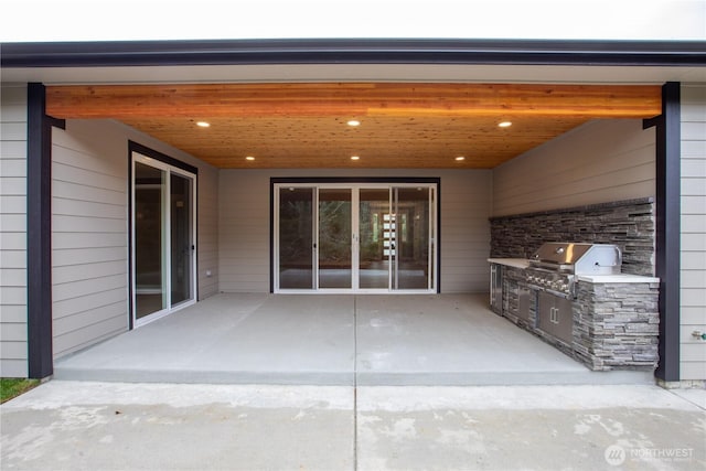 view of patio / terrace featuring a garage, area for grilling, and an outdoor kitchen