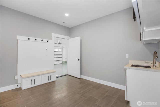 mudroom featuring wood tiled floor, baseboards, and a sink