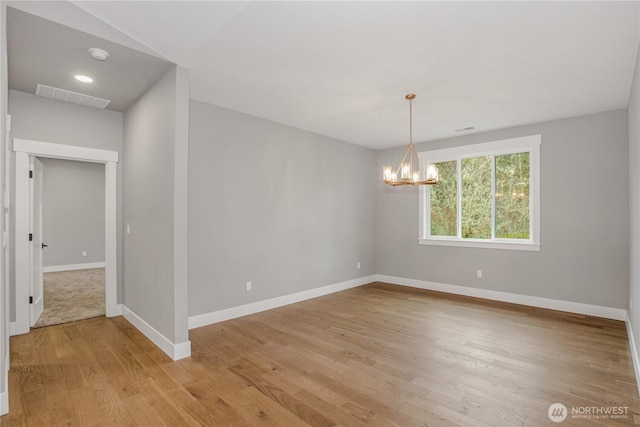 spare room featuring an inviting chandelier, light wood-style flooring, baseboards, and visible vents