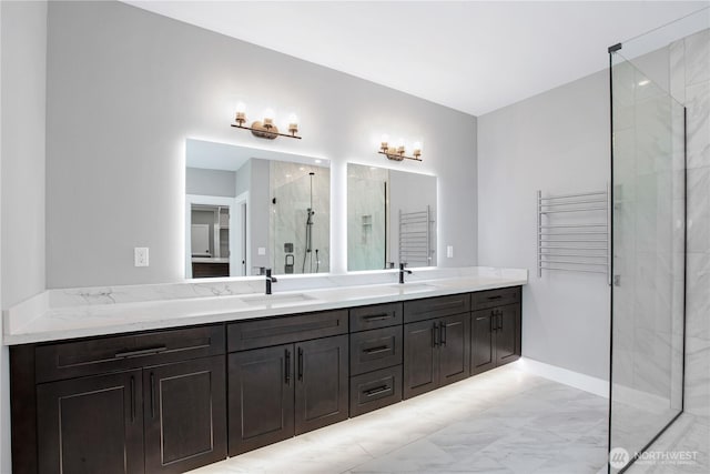 full bath with double vanity, marble finish floor, a stall shower, and a sink