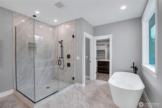 full bathroom featuring a walk in closet, marble finish floor, a shower stall, baseboards, and a soaking tub