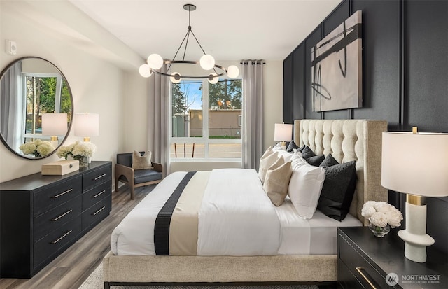 bedroom featuring a chandelier, multiple windows, and wood finished floors