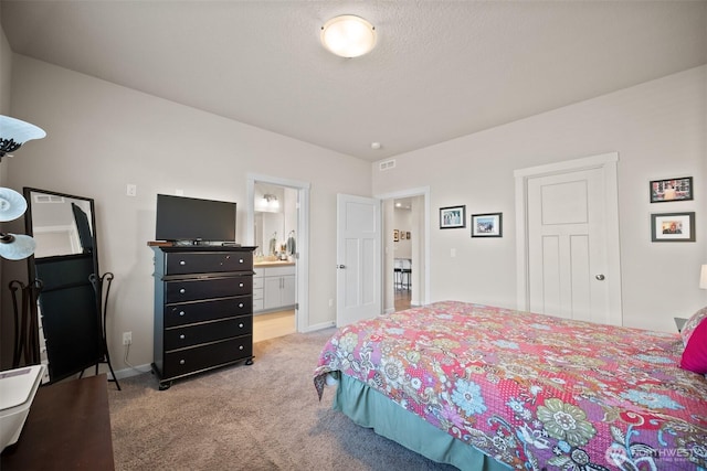 bedroom featuring visible vents, baseboards, light colored carpet, and ensuite bathroom