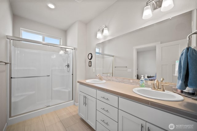 bathroom featuring a sink, a stall shower, and double vanity