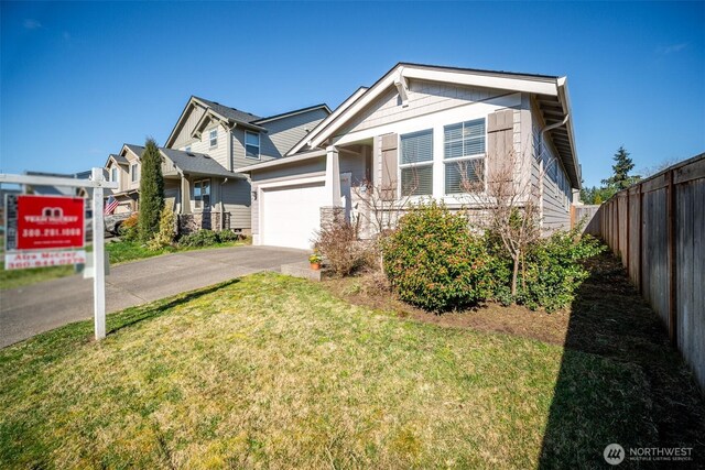 view of front of property with aphalt driveway, an attached garage, a front yard, and fence