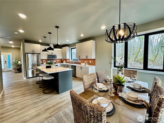 dining space with recessed lighting, baseboards, a notable chandelier, and light wood-style flooring