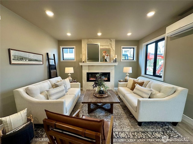 living room featuring a tiled fireplace, recessed lighting, an AC wall unit, and baseboards