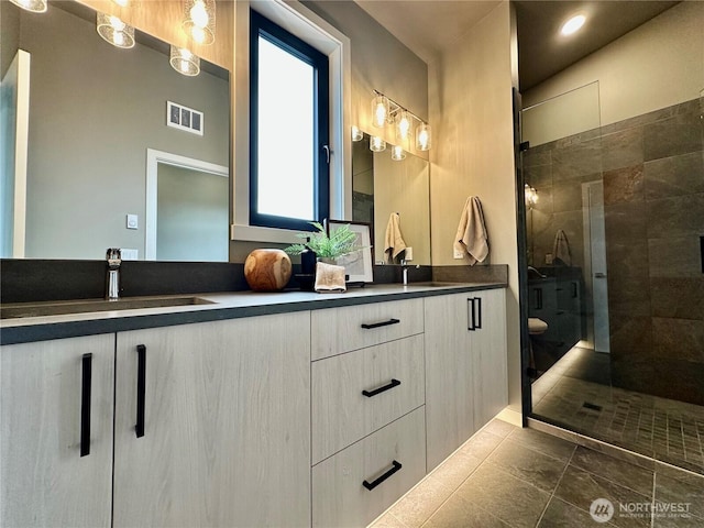 bathroom featuring double vanity, visible vents, a stall shower, and a sink