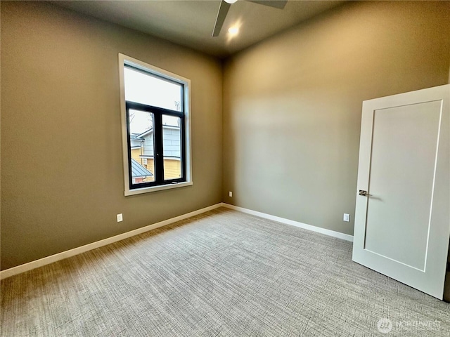 spare room featuring a ceiling fan, baseboards, and light carpet