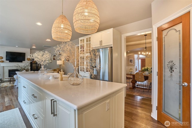 kitchen with glass insert cabinets, dark wood-type flooring, freestanding refrigerator, an inviting chandelier, and white cabinets