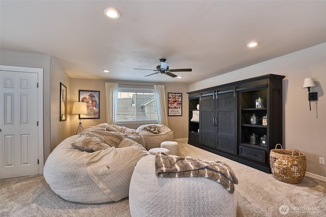 living room featuring ceiling fan, a barn door, recessed lighting, and light carpet