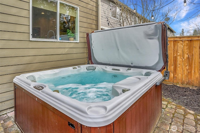 exterior space with wood walls, a hot tub, and brick floor