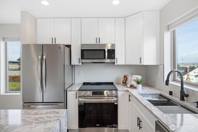 kitchen featuring a healthy amount of sunlight, appliances with stainless steel finishes, white cabinets, and a sink