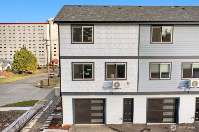 townhome / multi-family property with ac unit, an attached garage, and a shingled roof