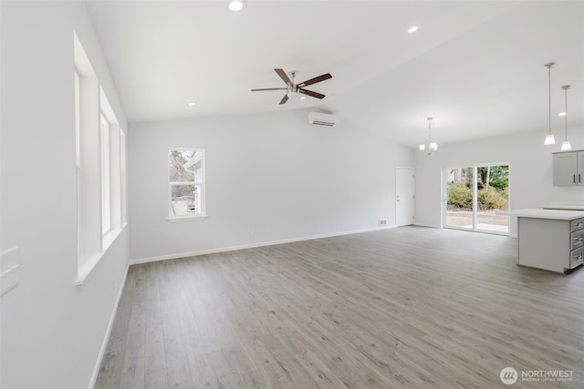 unfurnished living room with a wall unit AC, light wood finished floors, baseboards, ceiling fan, and vaulted ceiling