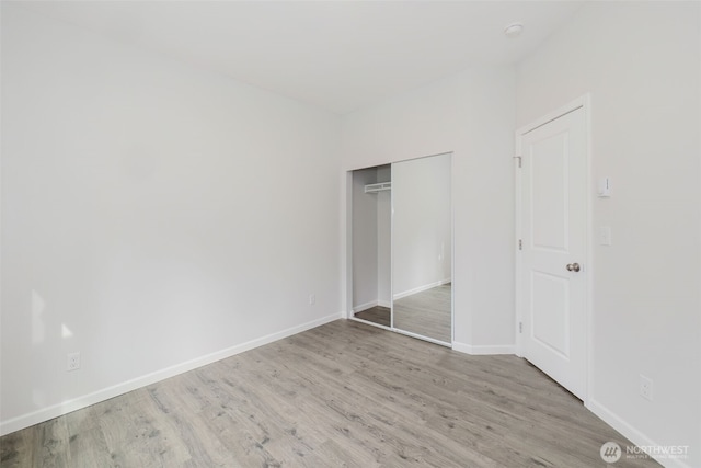 unfurnished bedroom with a closet, baseboards, and wood finished floors