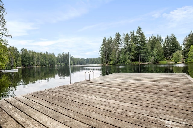 view of dock featuring a wooded view and a water view