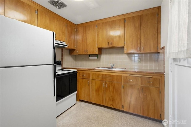 kitchen with visible vents, freestanding refrigerator, a sink, range with electric cooktop, and brown cabinets