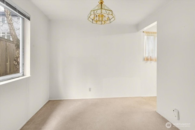 unfurnished room with an inviting chandelier and carpet