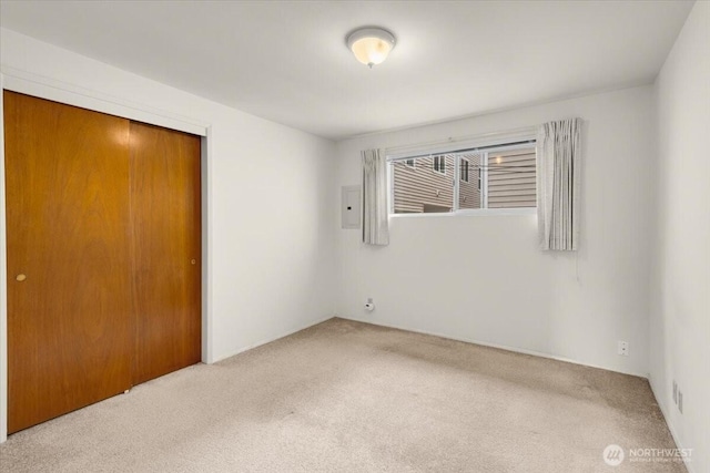 unfurnished bedroom with a closet, electric panel, and carpet