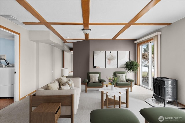 living area with visible vents, separate washer and dryer, baseboards, light colored carpet, and a wood stove