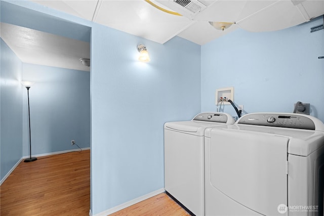 clothes washing area featuring washer and dryer, baseboards, wood finished floors, and laundry area