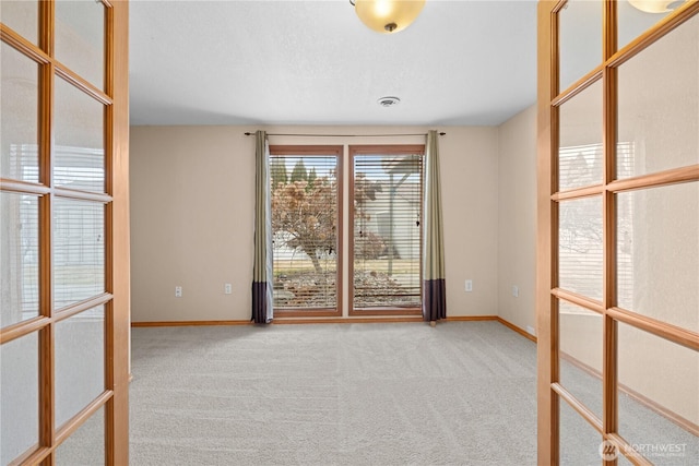 carpeted empty room featuring visible vents, baseboards, and french doors